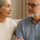 Casal idoso conversando no sofá, representando apoio e diálogo na andropausa na terceira idade.